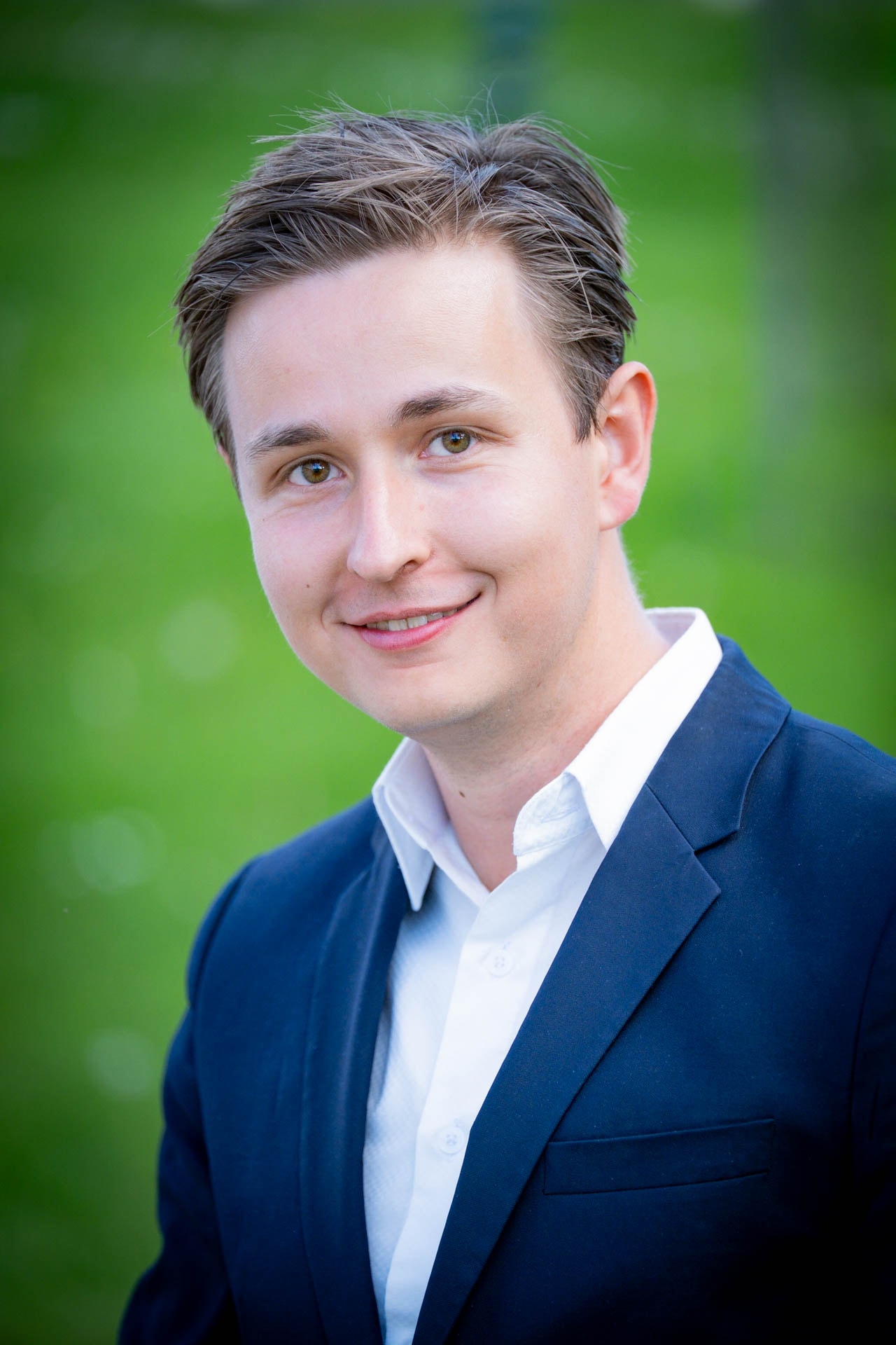Constantin Weigel, CDU-Bürgermeisterkandidat für Clausthal-Zellerfeld, im dunklen Sakko vor grünem Hintergrund